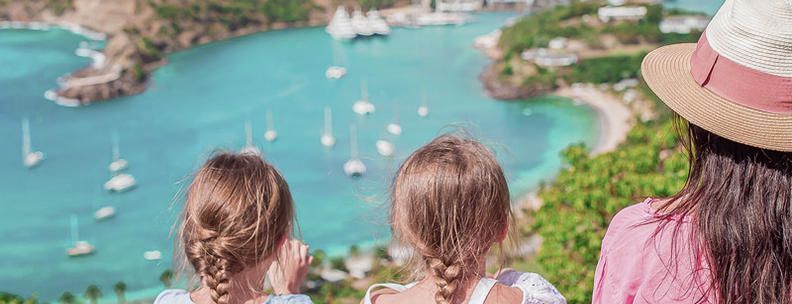 Frau und zwei Mädchen sitzen am Meer im Urlaub