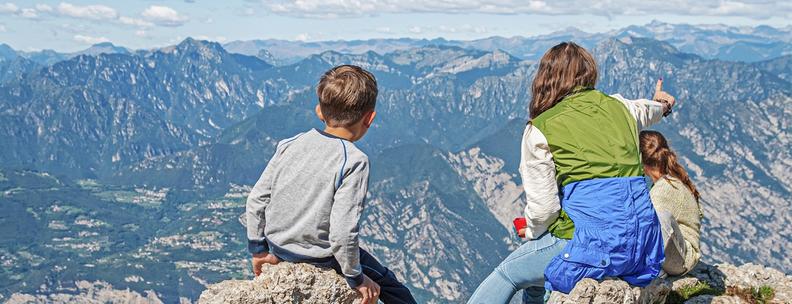 Familie mit Blick auf die Berge und den Gardasee auf dem Gipfel des Monte Baldo, Alpen, Italien