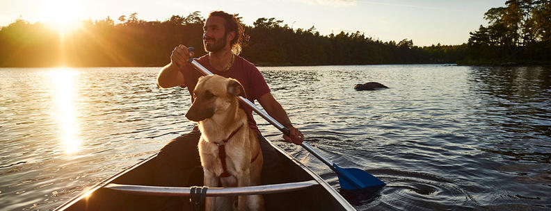 Mann mit Hund im Kanu